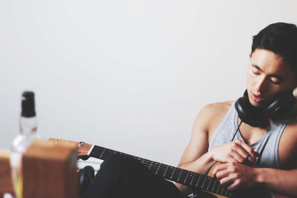 human man holding guitar wearing headphones male
