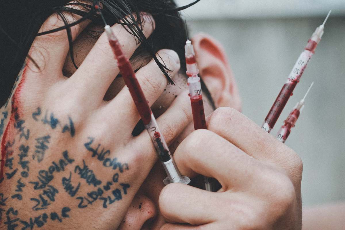 human man holding syringes of red stain people