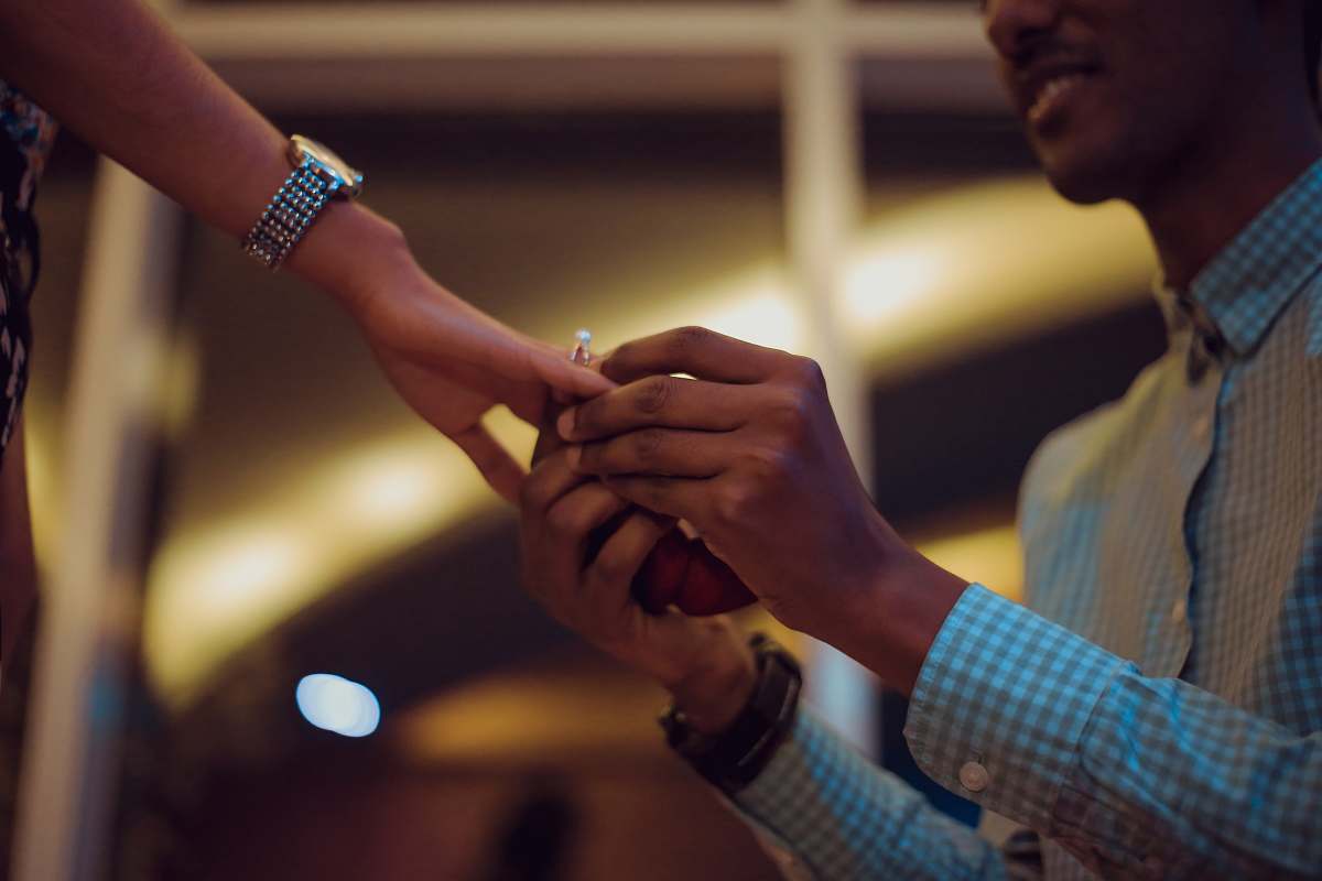human man putting ring on woman's hand finger