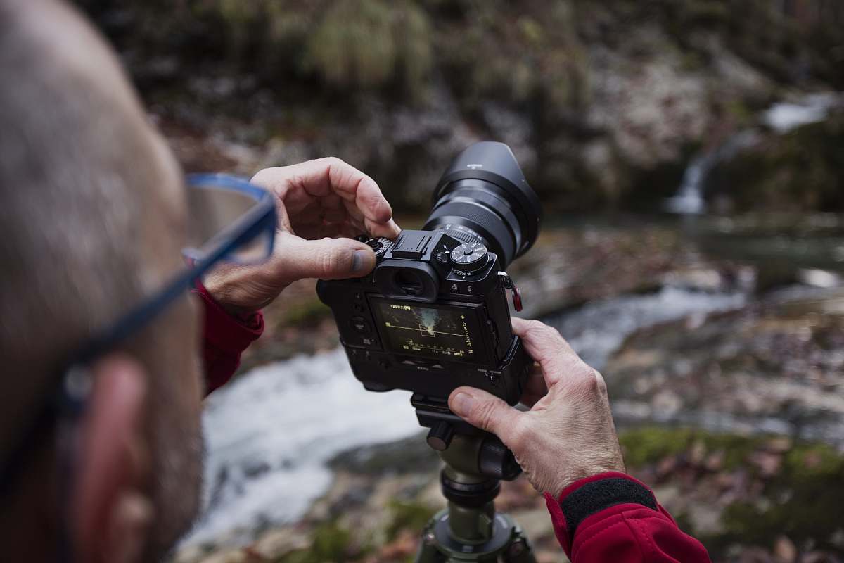 human man taking photo of river using DSLR camera camera