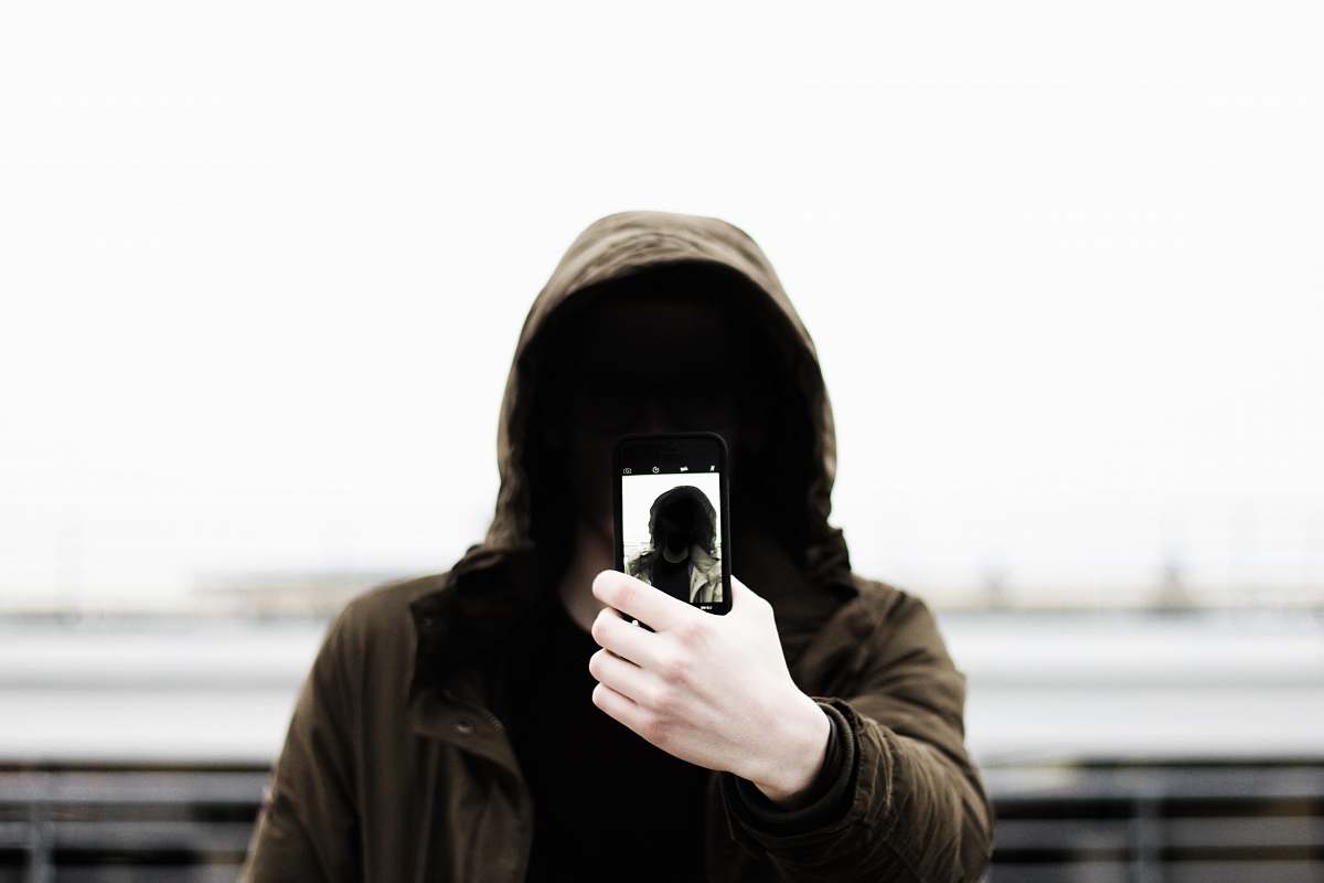 human man wearing black hooded jacket and holding smartphone white taking close-up selfie people