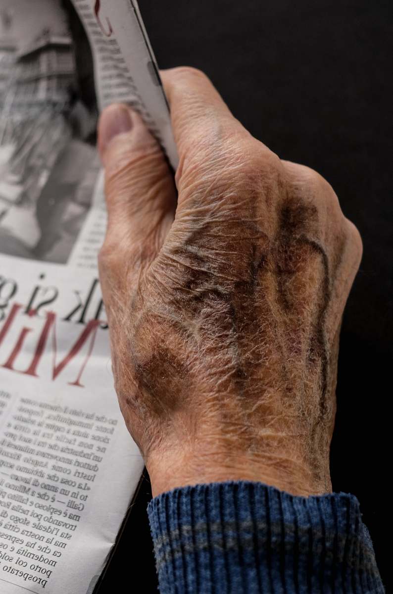 human man wearing blue long sleeve top holding newspaper hand