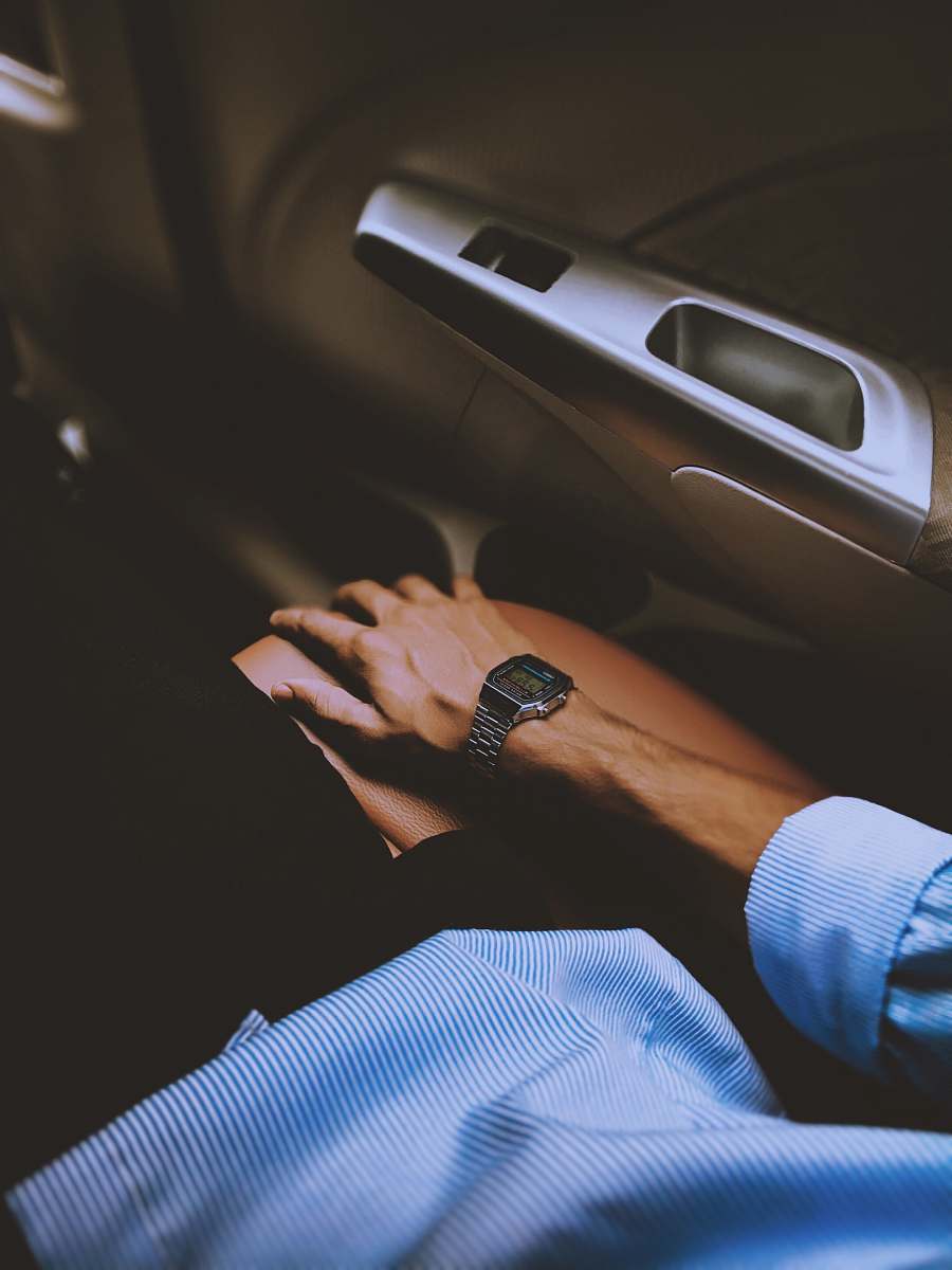 human man wearing digital watch sitting inside vehicle wristwatch