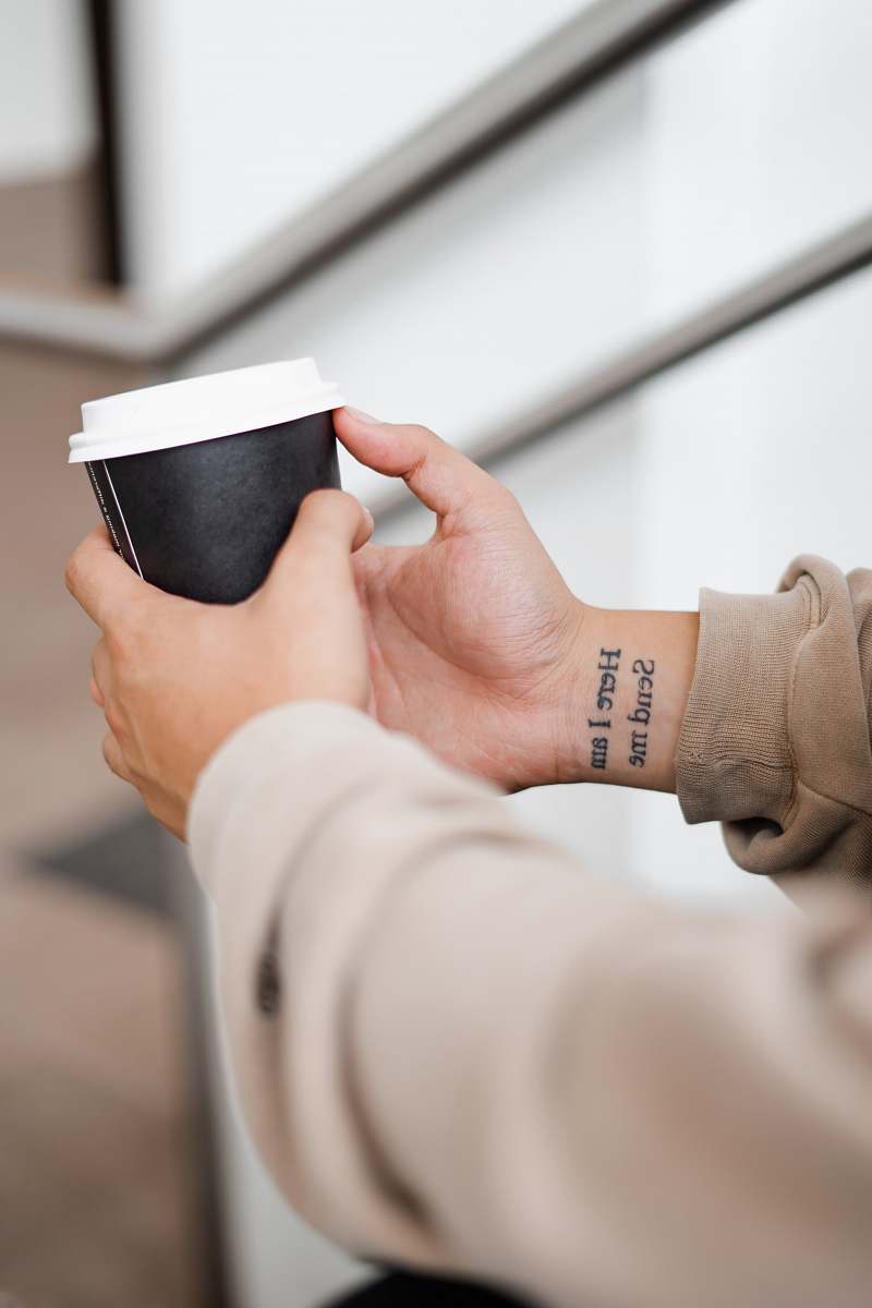 human person holding black and white coffee cup cup