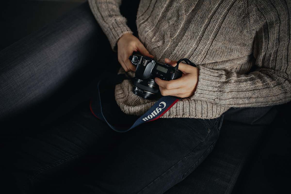 camera person holding black DSLR camera photographer