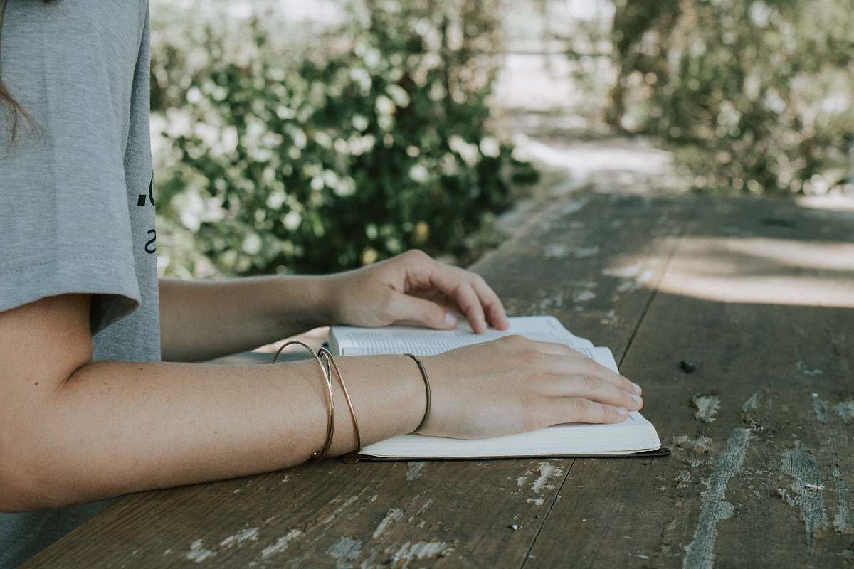 human person holding book white sitting in front of desk bible