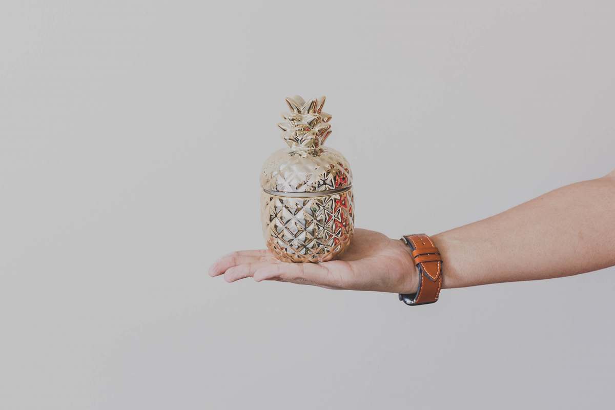 human person holding gold-colored pineapple design rack wristwatch