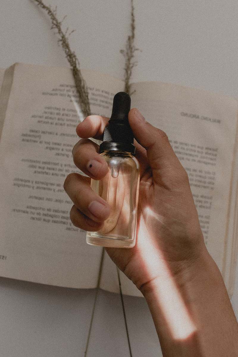 human person holding small clear drop bottle finger