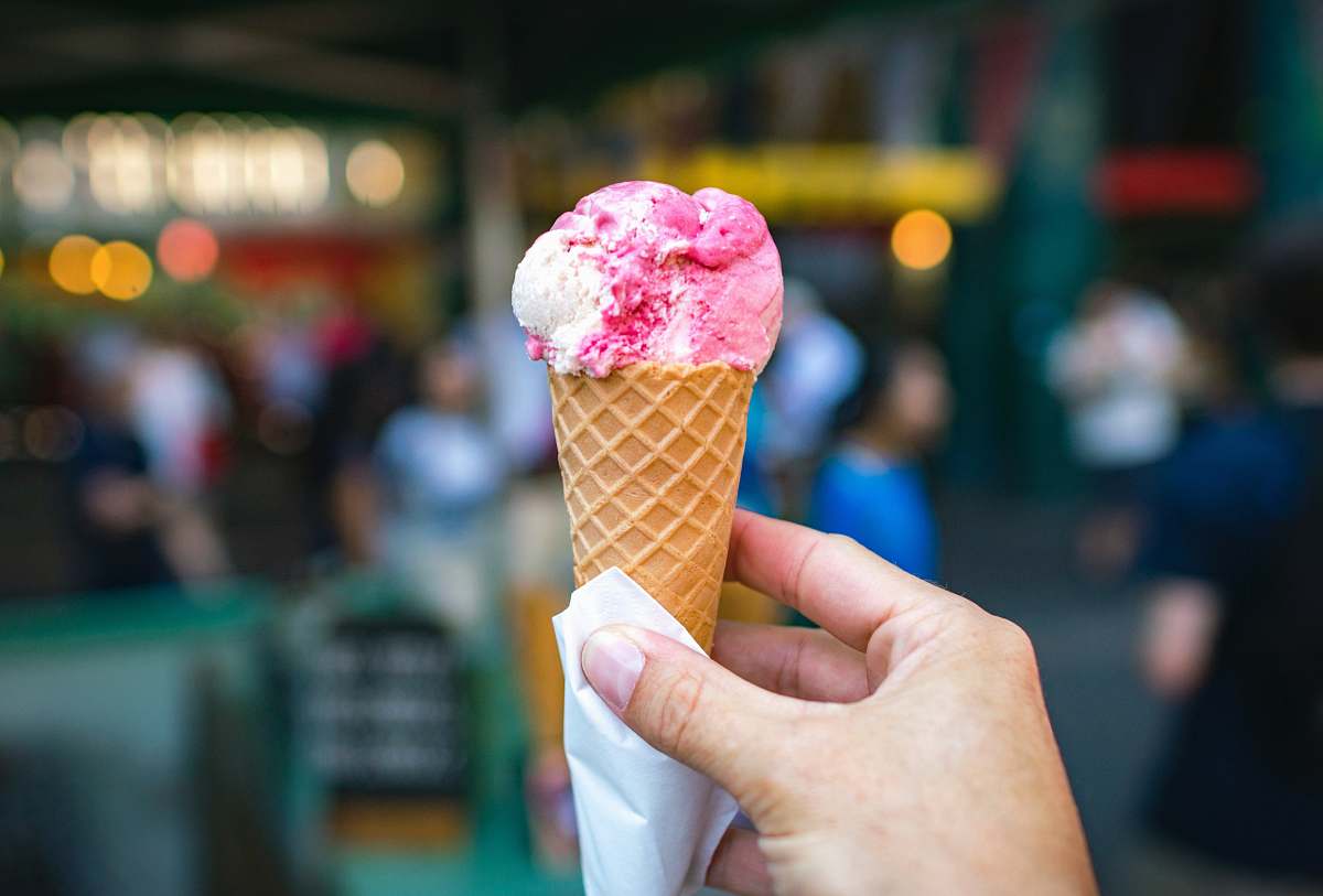 human person holding white and pink ice cream in cone shallow focus photography ice cream