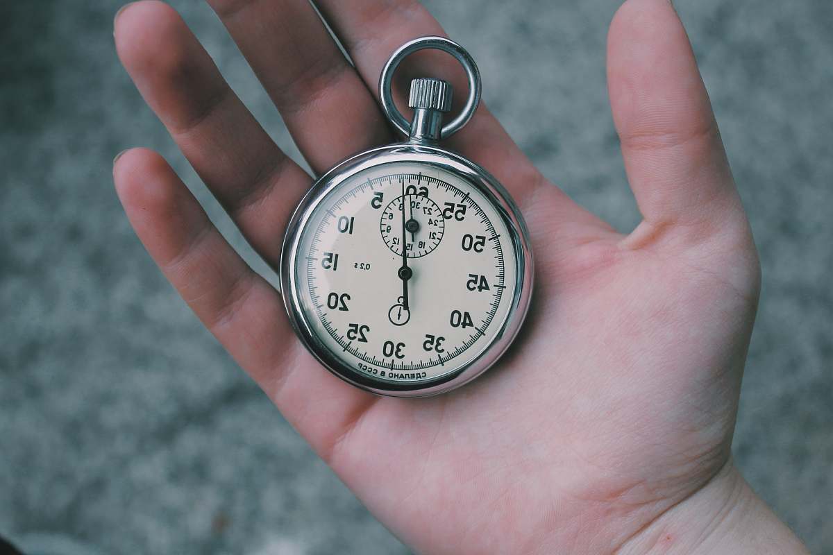 time person holding white and silver-colored pocket watch stopwatch