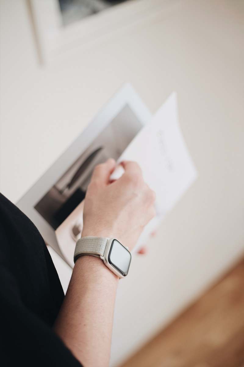 human person holding white hardbound book wristwatch