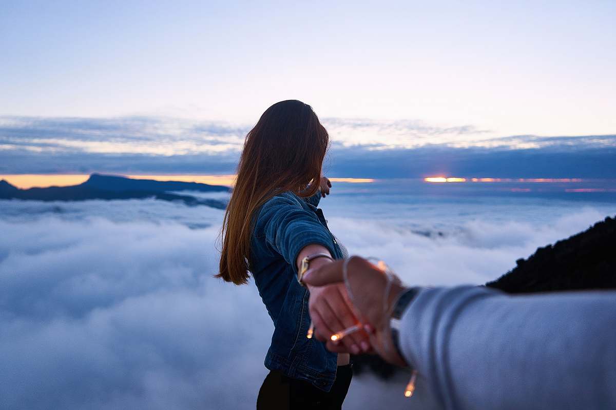 people person holding woman's hand on top of hill couple