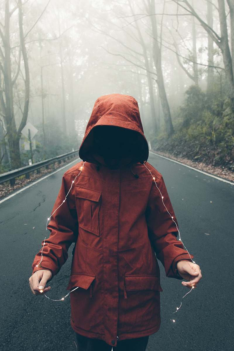 people person in red hooded jacket holding string lights pocket