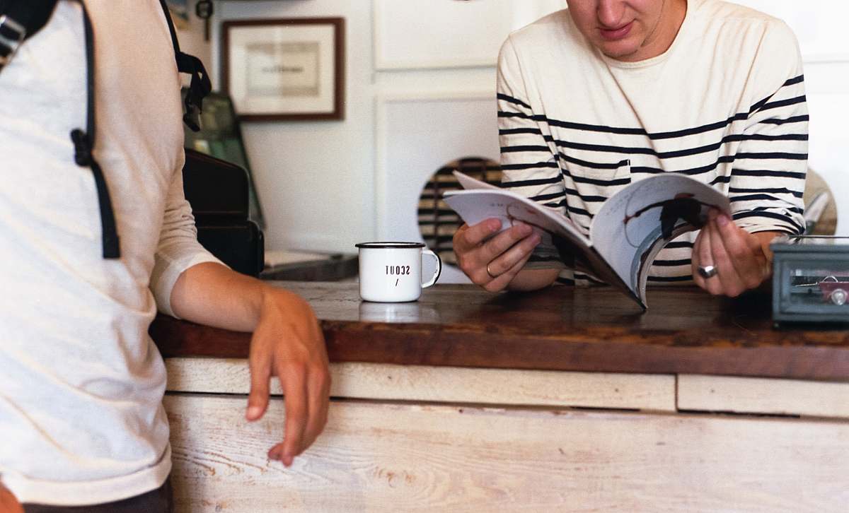 people person leaning on table while reading book cup