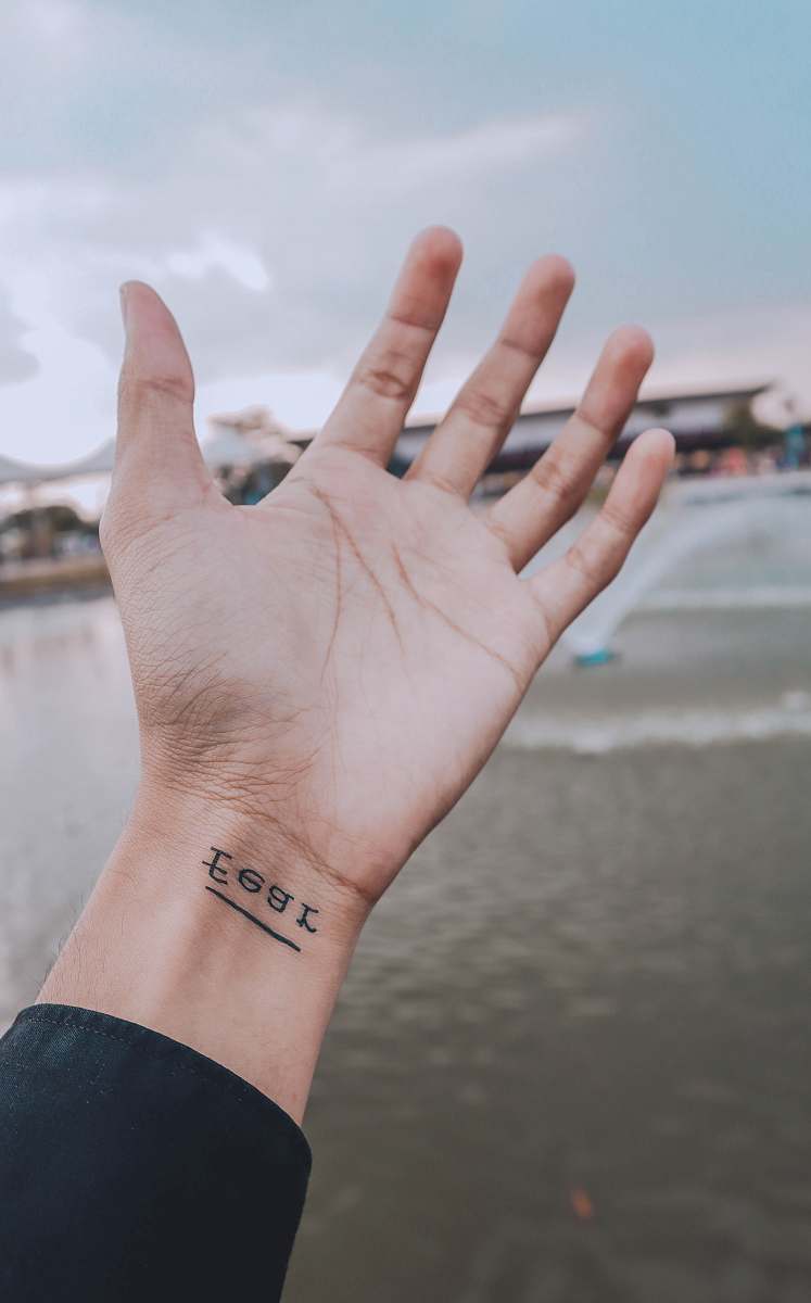 human person showing right wrist with fear tattoo hand