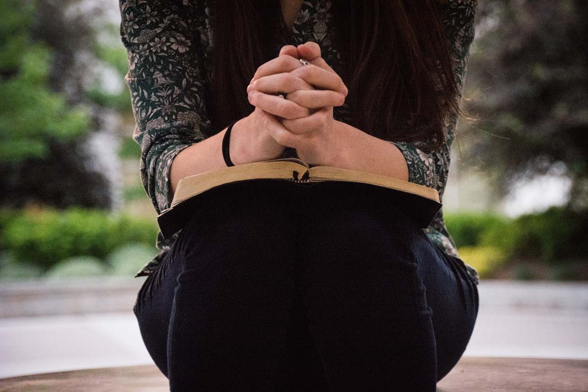 human person sitting while reading book bible