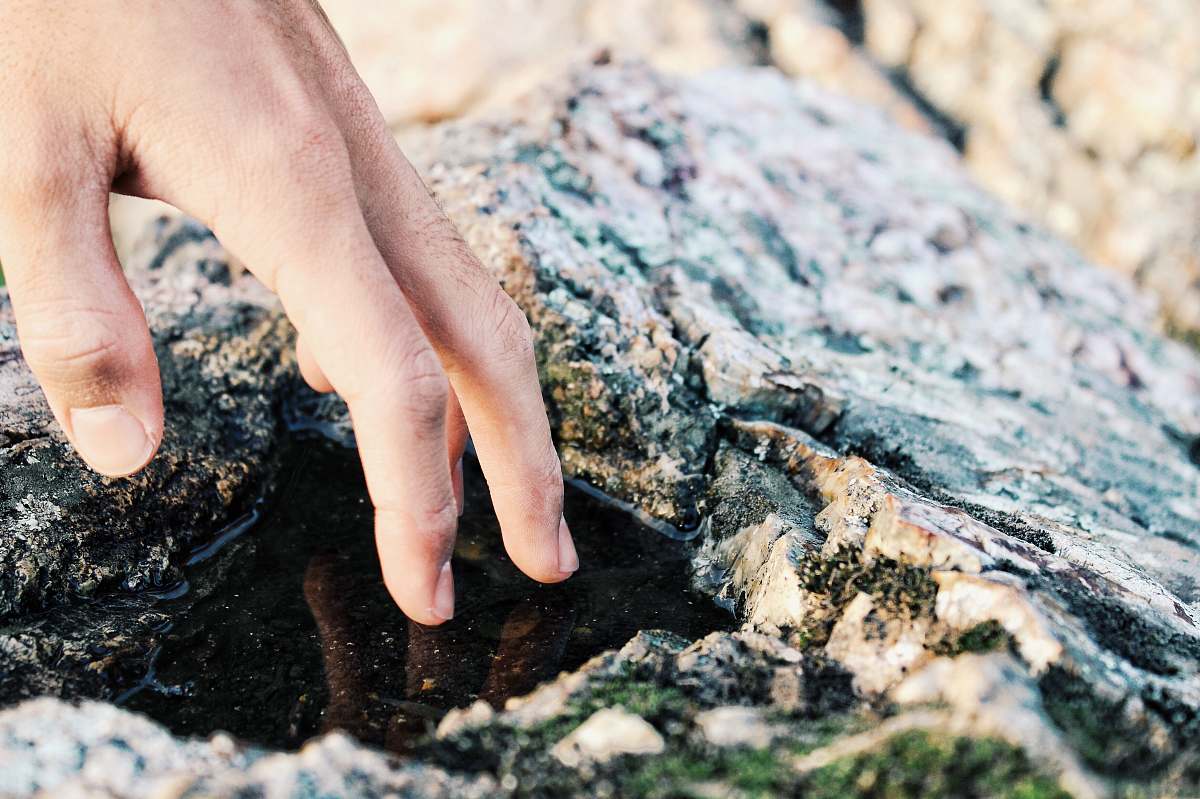 human person touching water rock