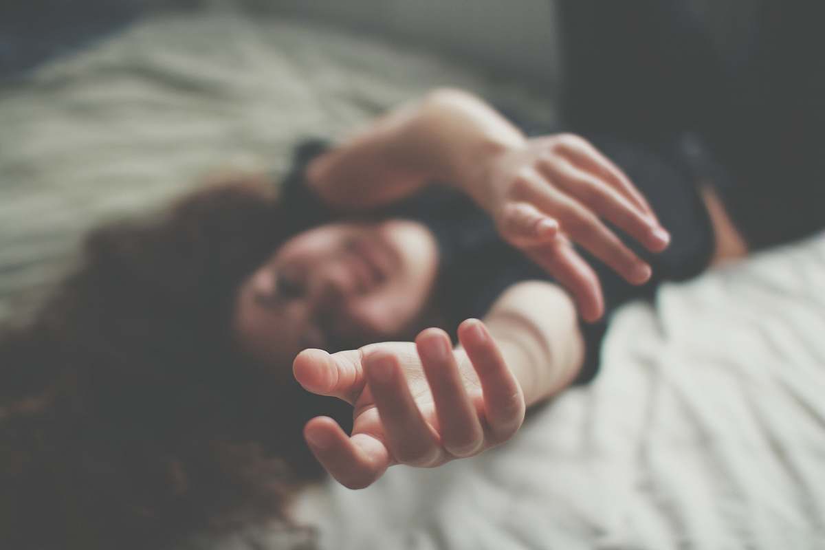 hand selective focus photography of woman lying bed finger