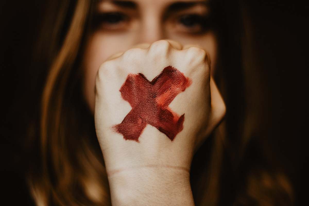 human selective focus photography of woman showing her left hand with x painting finger