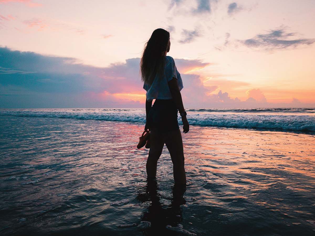 human woman in white shirt and shorts on sea water standing