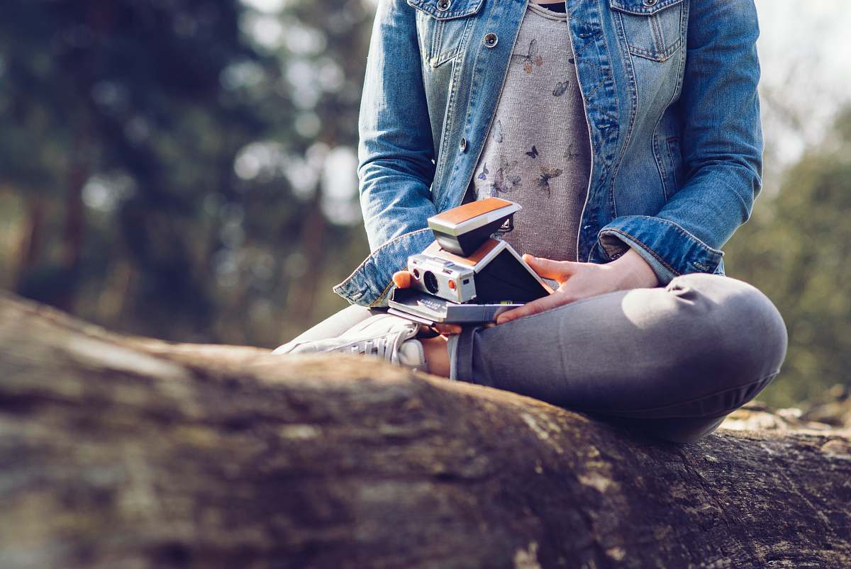 human woman sitting on log holding camera and book people