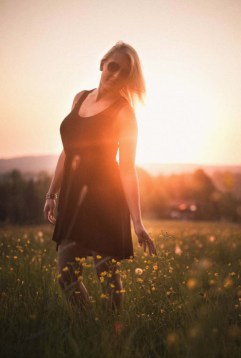 people woman wearing black scoop-neck mini dress surrounded by flowers during sunset woman