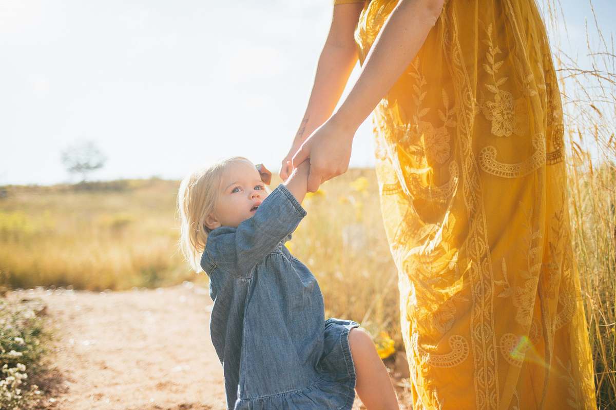 human woman wearing yellow dress holding hands of girl during daytime holding hands