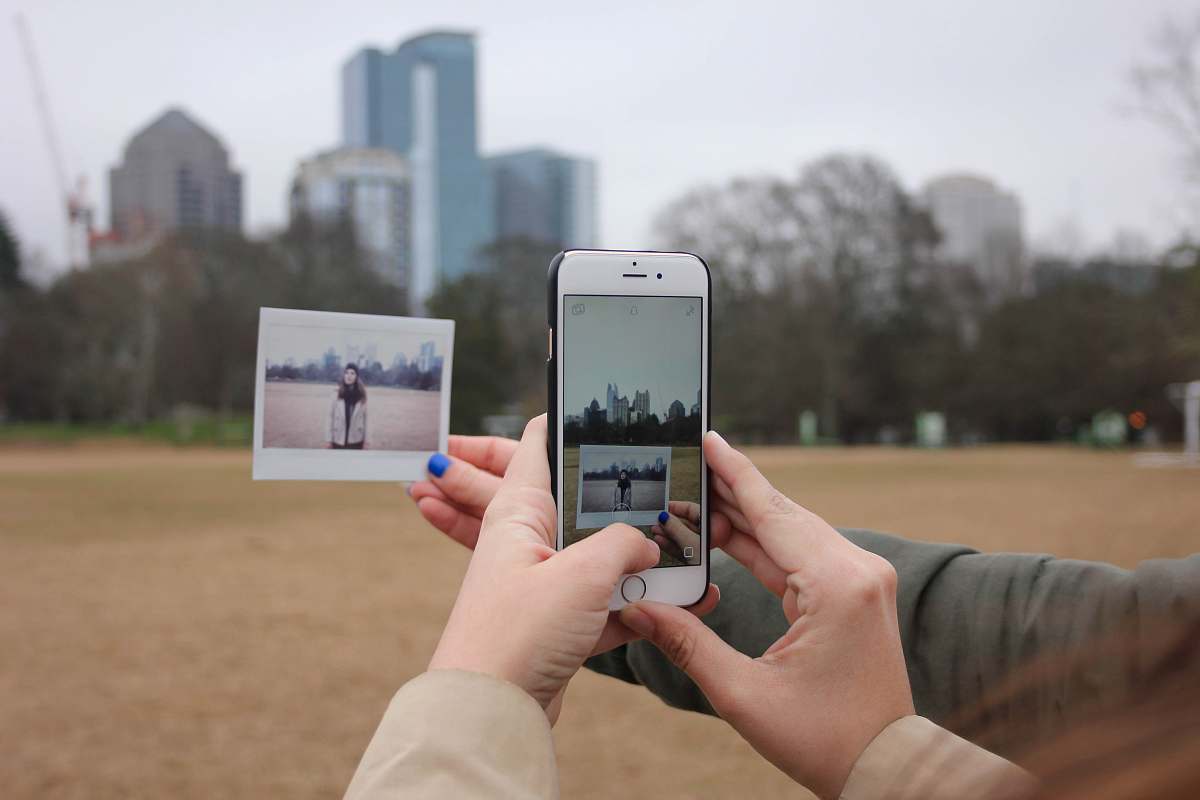 polaroid person holding silver iPhone 6 with black case iphone