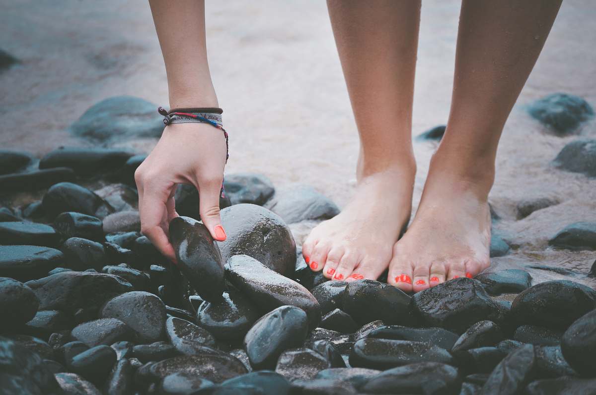 nail person picking a black wet stone legs