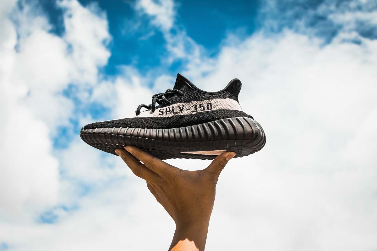 shoes unpaired adidas Yeezy Boost 350 V2 shoe on person's hand sky