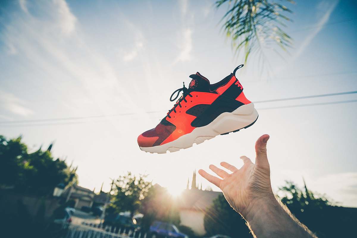 person unpaired orange and white Nike Air Huarache sunset