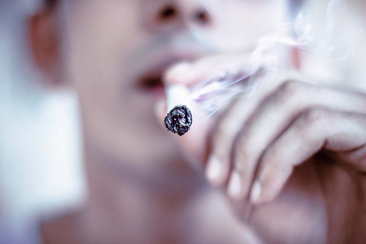 cigarette selective focus of man hitting cigarette joint