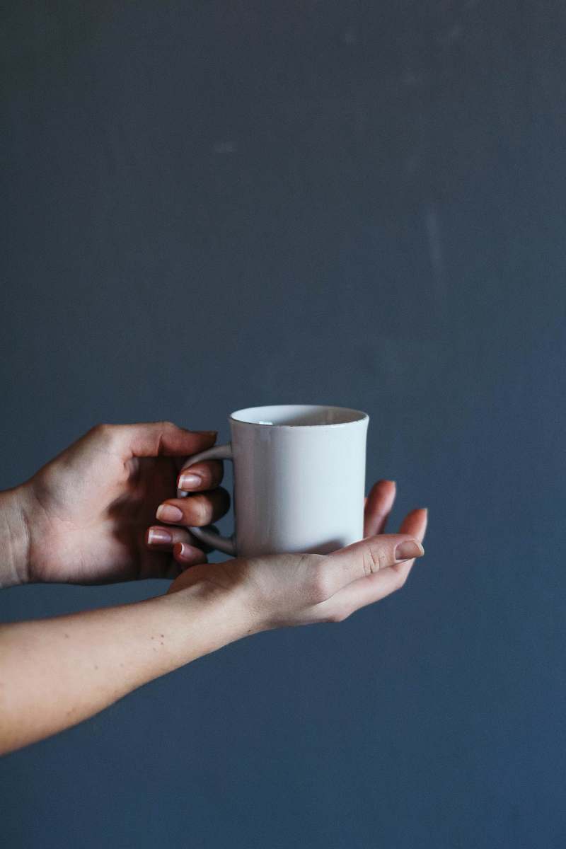 hand person holding grey ceramic mug coffee