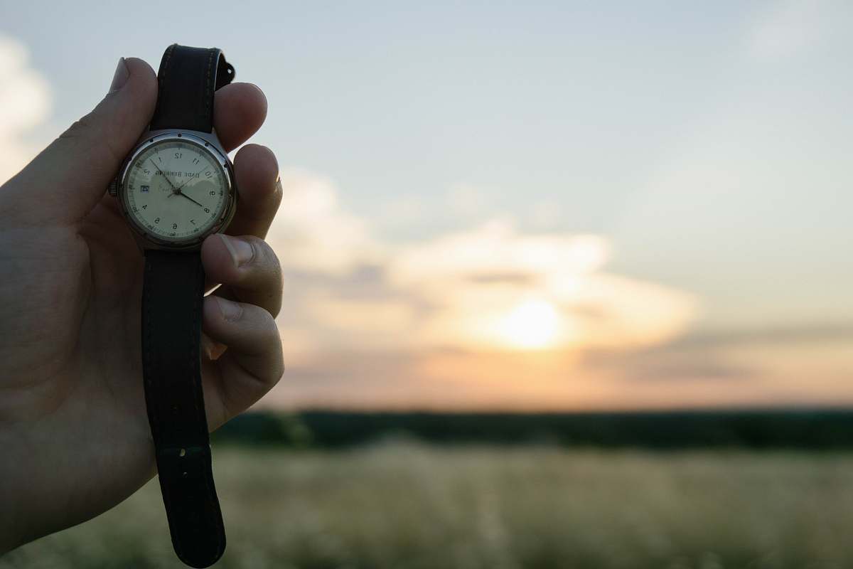 wristwatch person's hand holding round silver analog watch with black leather strap time