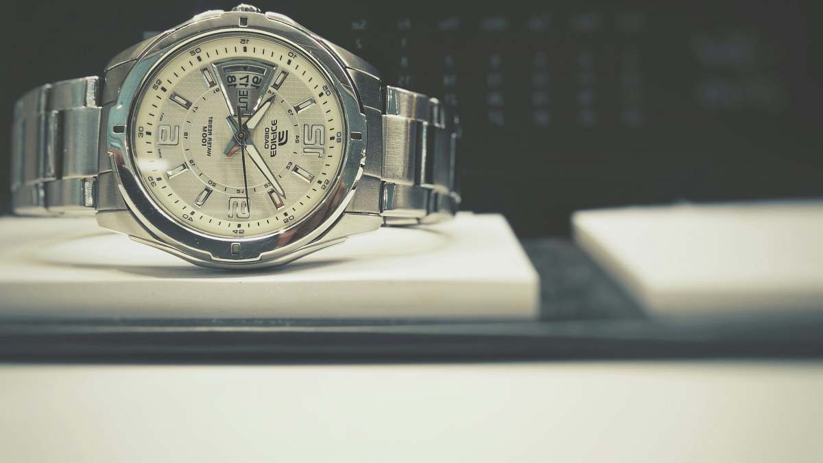 hand round silver-colored bezel analog watch with link bracelet on white board face