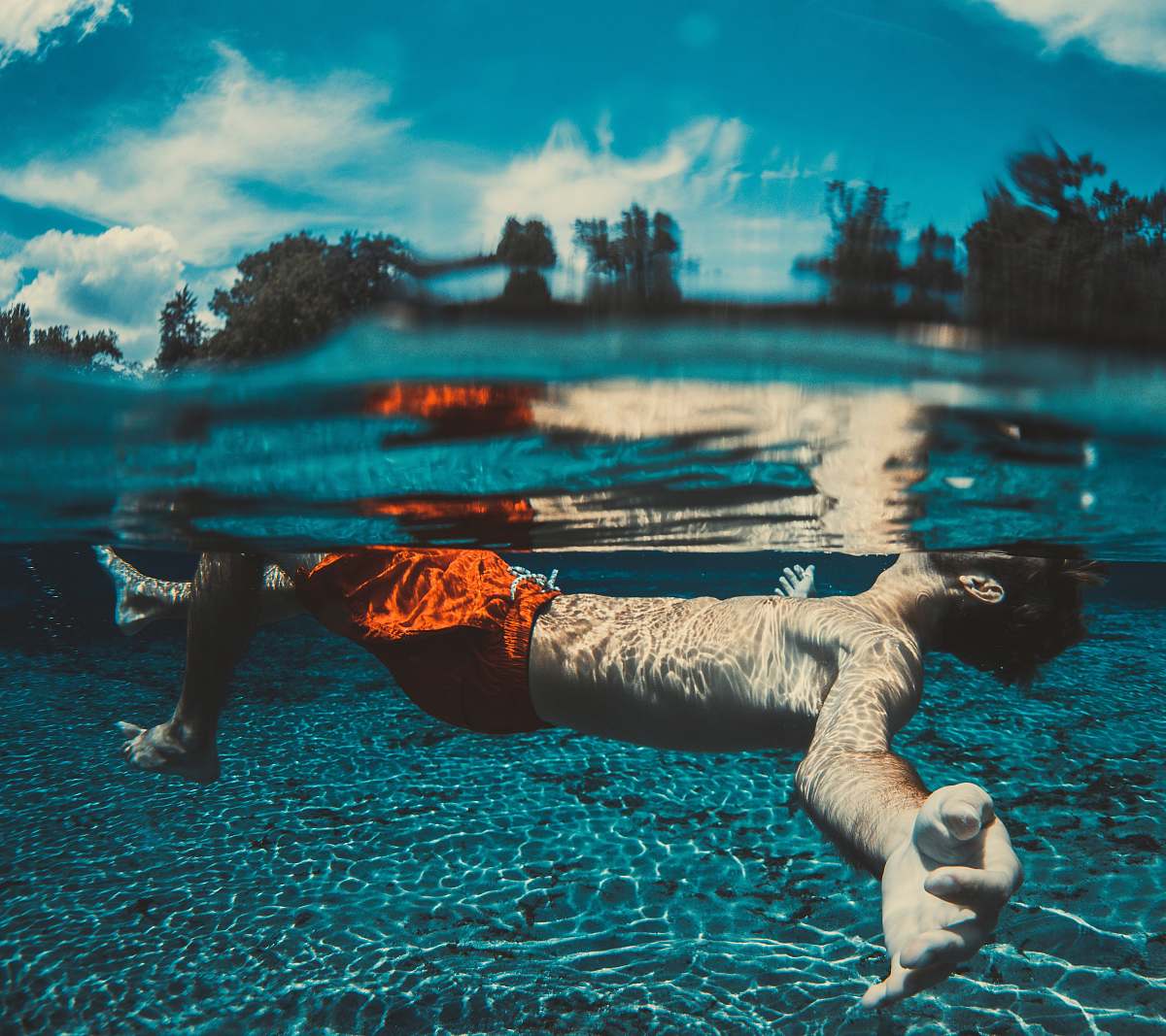 male underwater photography of floating man wearing red shorts boy