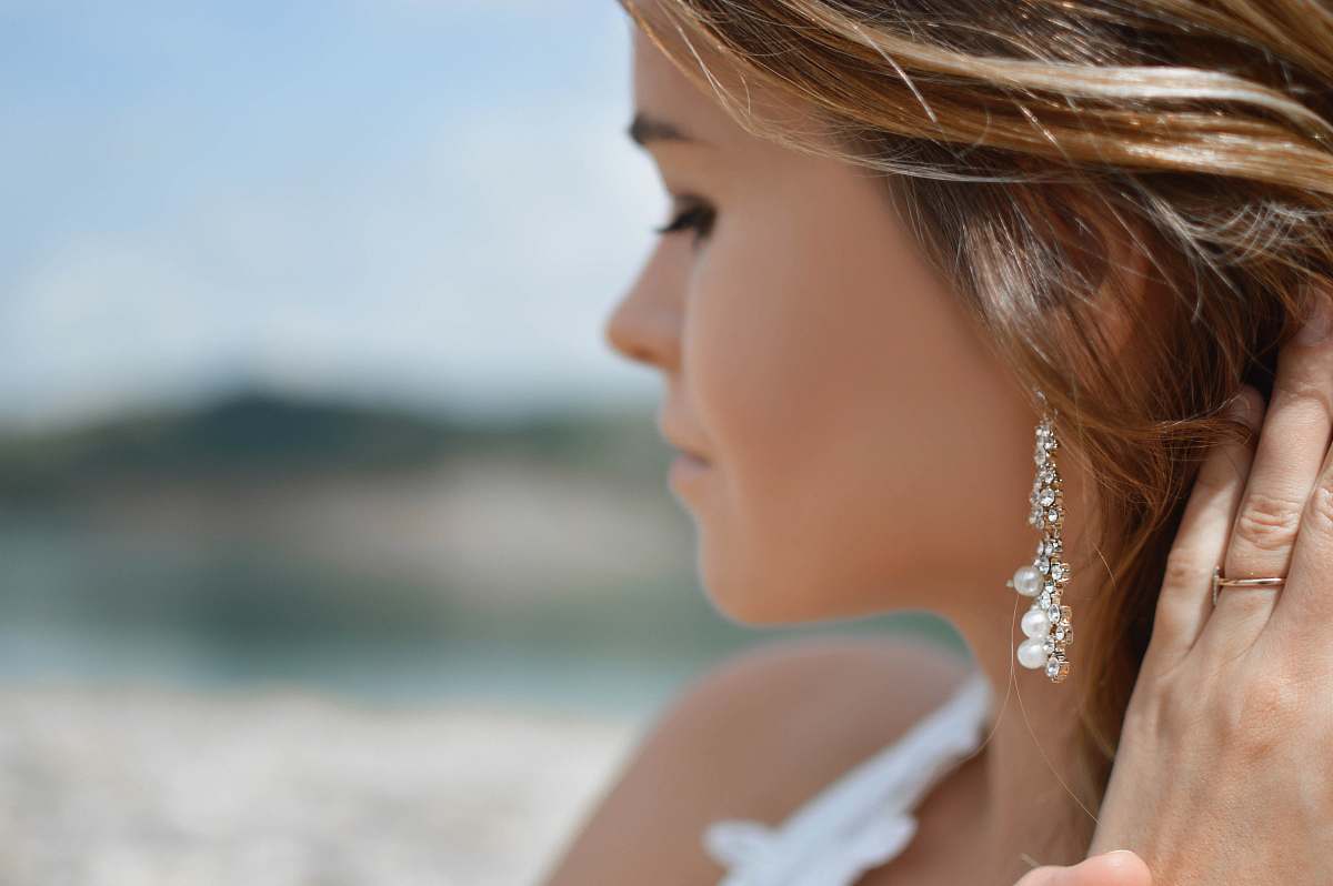 earring shallow focus photography of woman wearing dangling earrings holding her hair near mountain female