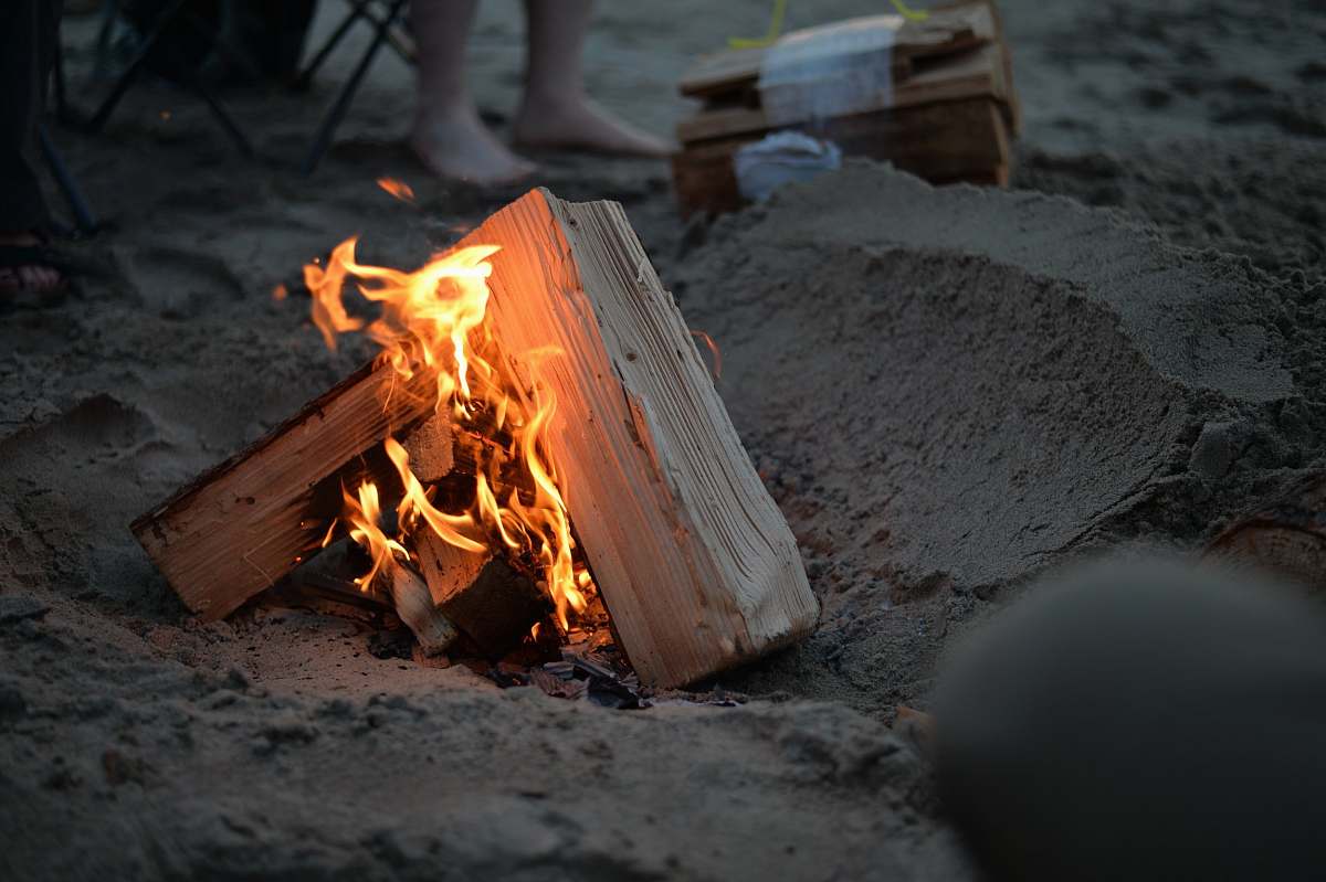 bonfire campfire on sand near person campfire