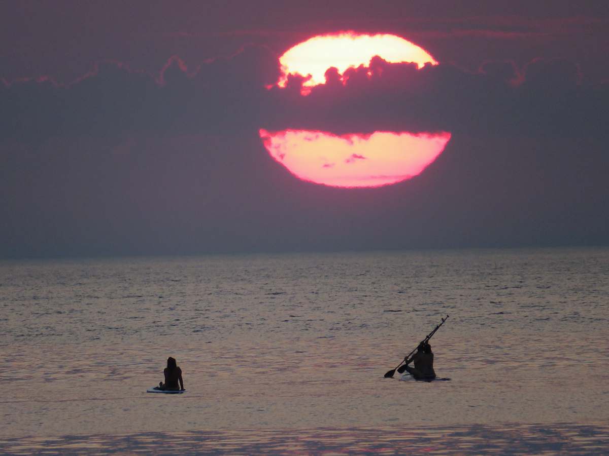 flame person riding on boat under gray sky during daytime la barceloneta