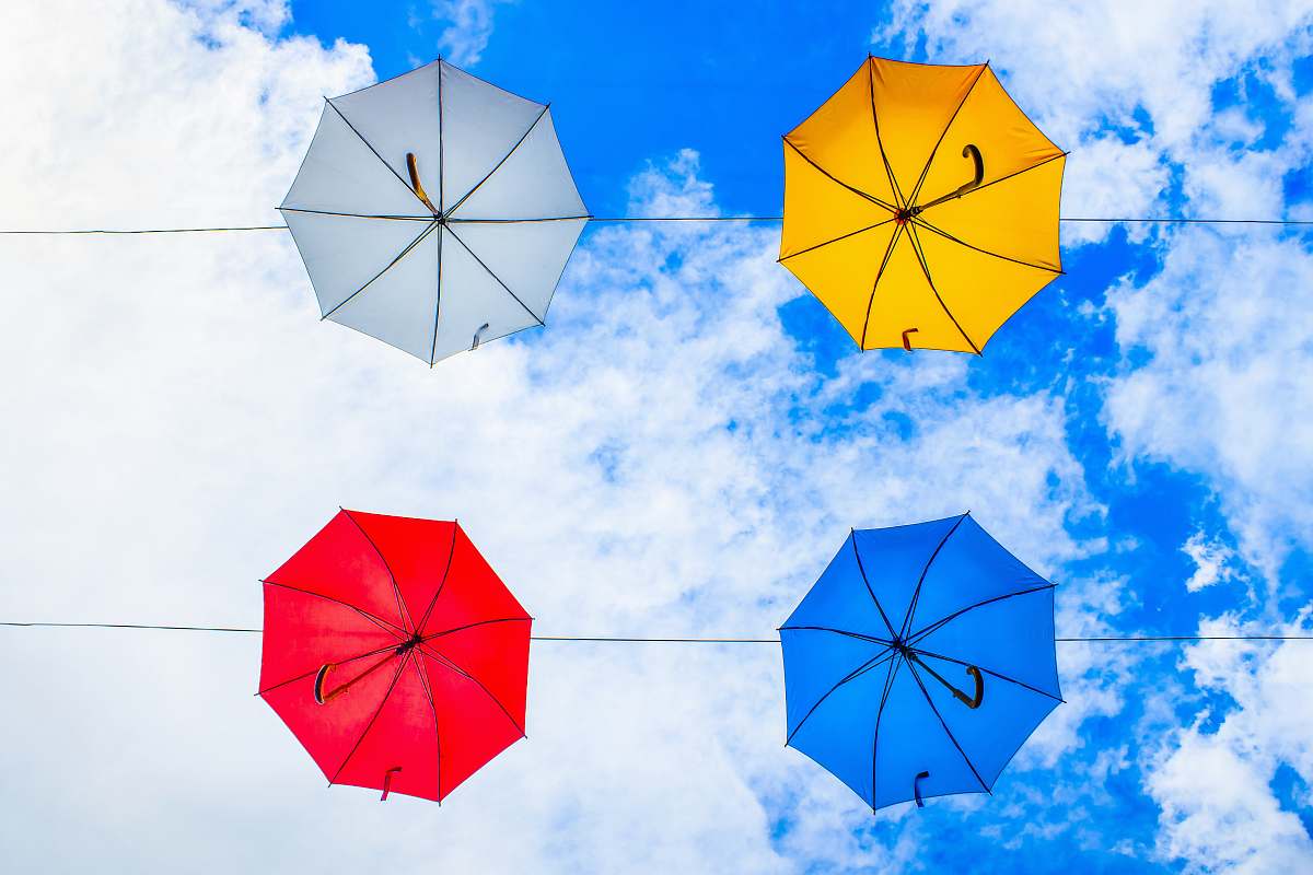  four assorted-color umbrellas hanged on cable under cloudy sky 