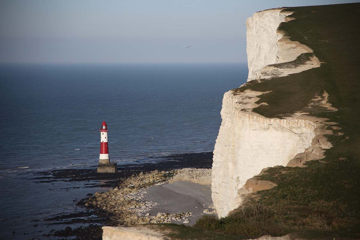  photo of red and white lighthouse at seashore 