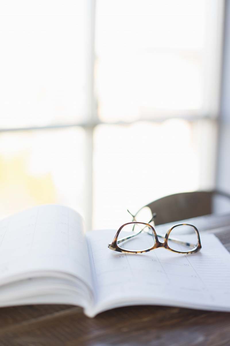 accessory brown framed eyeglasses on top of open book glasses