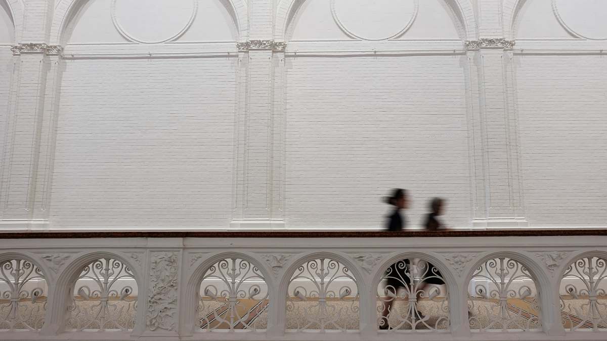 busy time-lapse photography of two person walking at hallway between concrete fence and wall fast