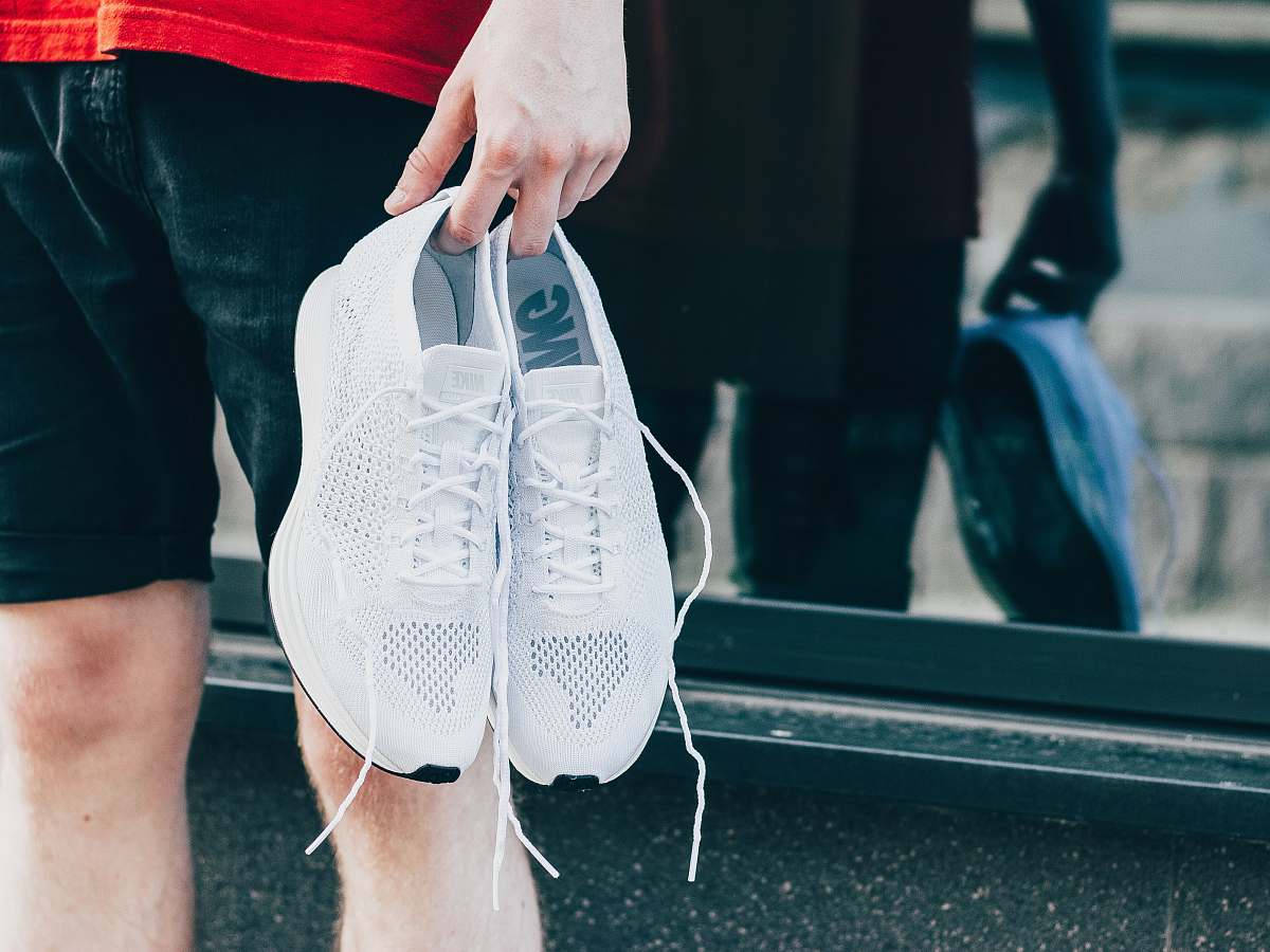clothing person holding white low-top shoes footwear