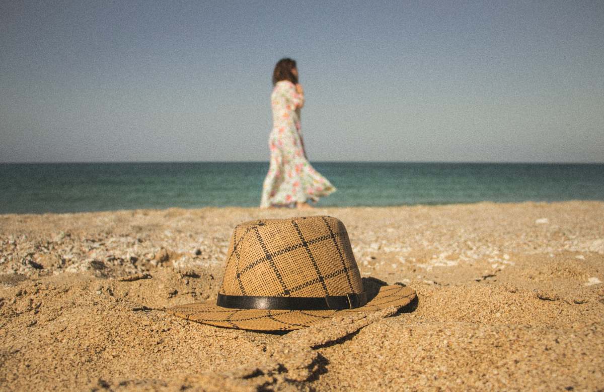 clothing woman walking near seashore and brown and gray hat on brown sand hat