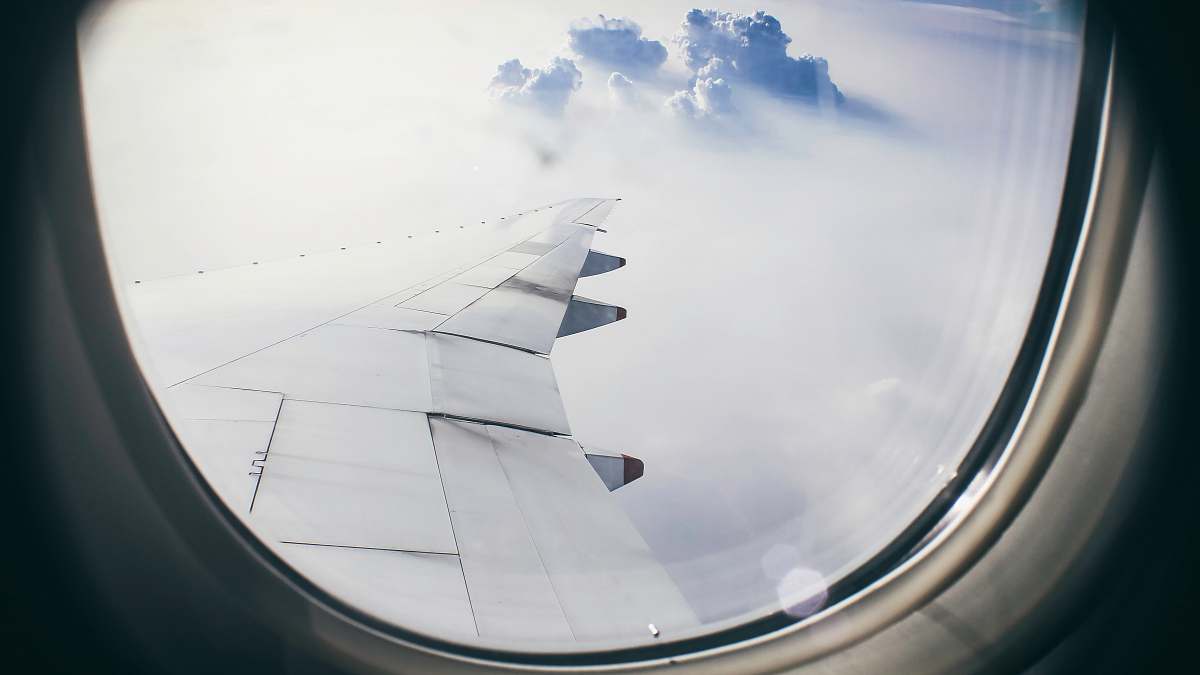 window architectural photography of plane's wing above clouds during flight grey