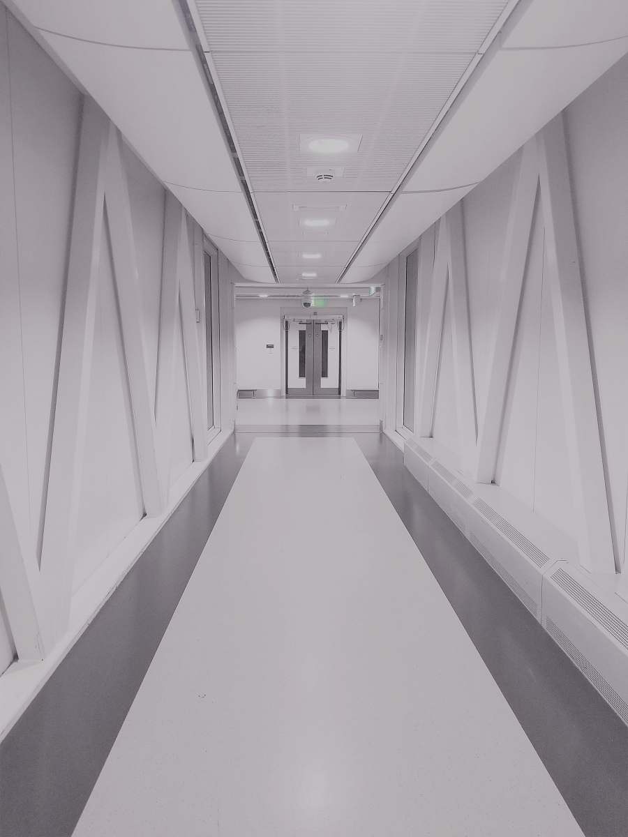 grey person taking photo of white and gray hallway corridor