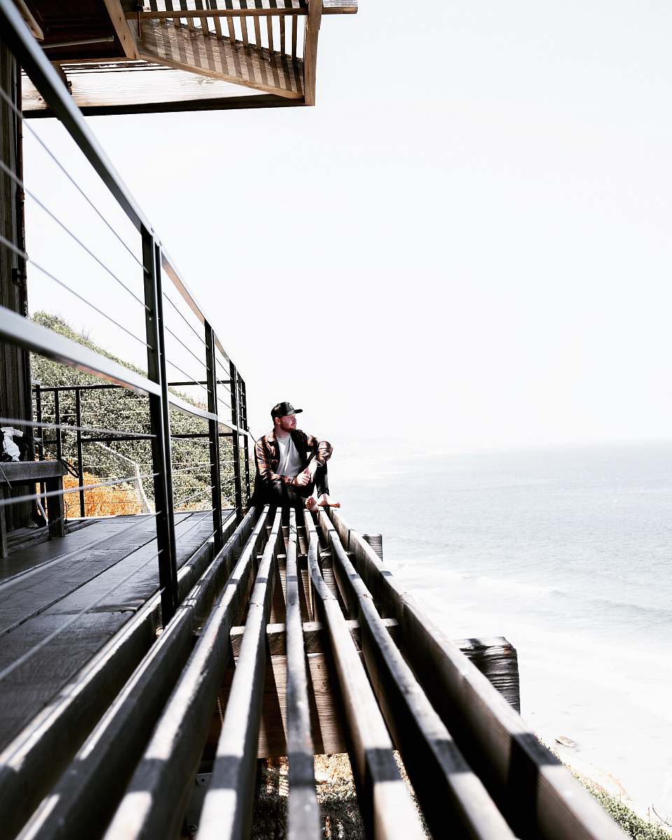 handrail man sitting on grey surface near ocean railing