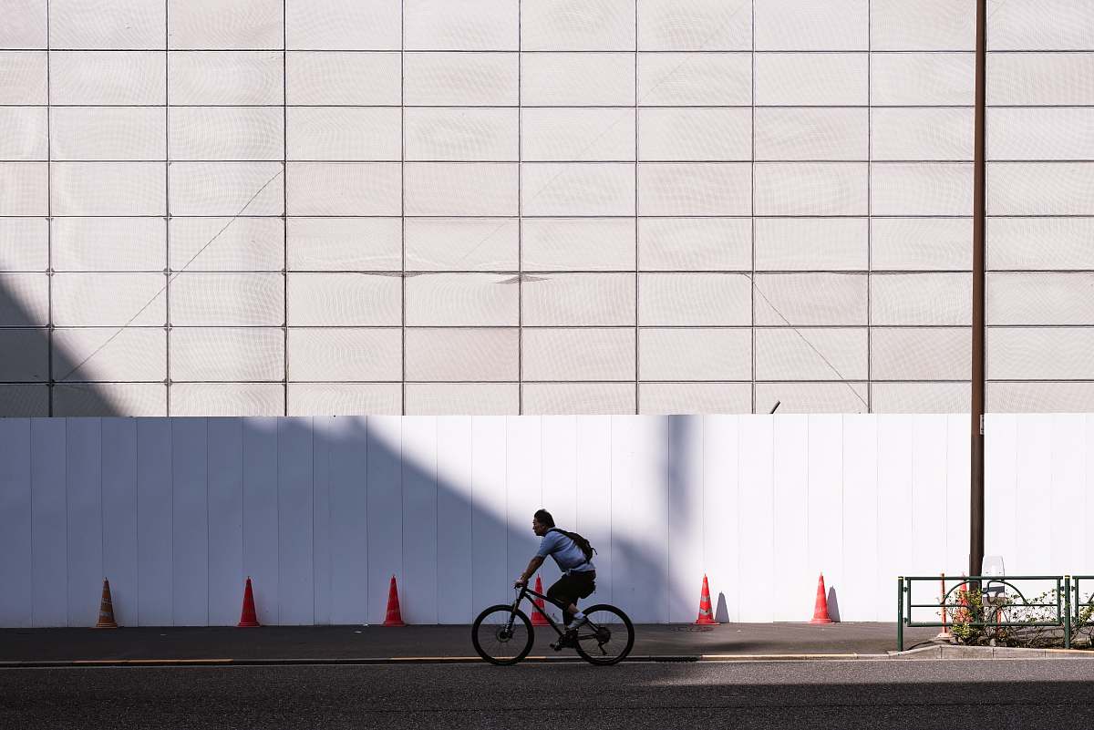 bike man riding bicycle near white wall during daytime japan