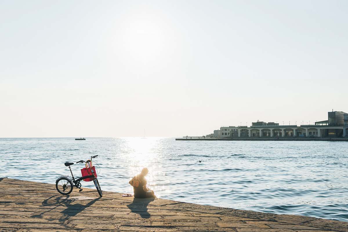path person sitting on shore beside bicycle walkway